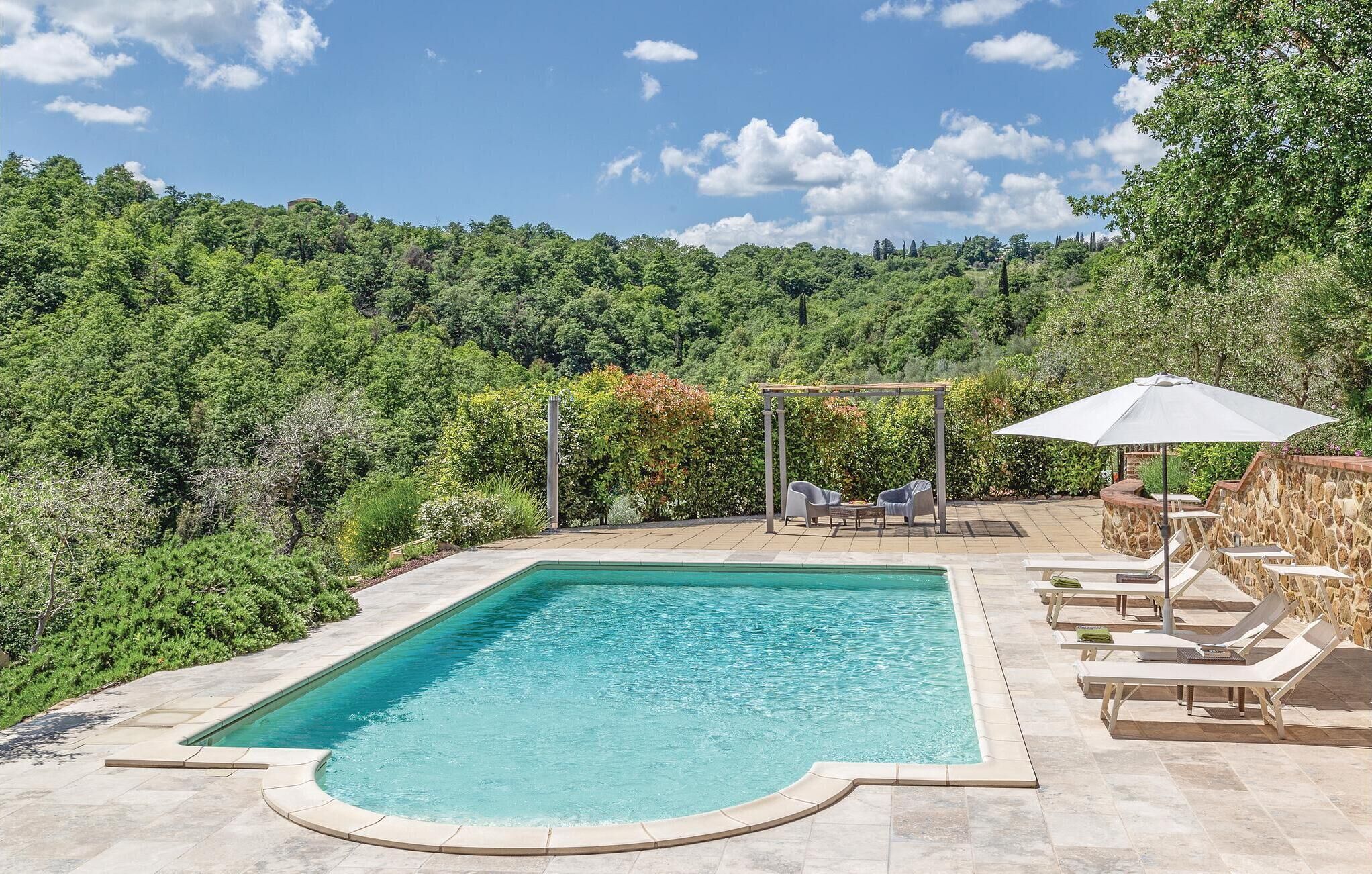 Une piscine rectangulaire agrémentée d’une pergola et de chaises longues, le tout aménagé dans un jardin paysager.