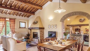 Una sala de estar acogedora con chimenea, un comedor y una cocina visibles a través de un arco.