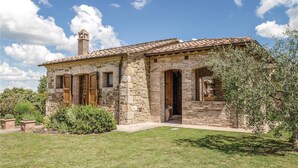 Una casa de piedra con techo de tejas, chimenea y puerta de madera.