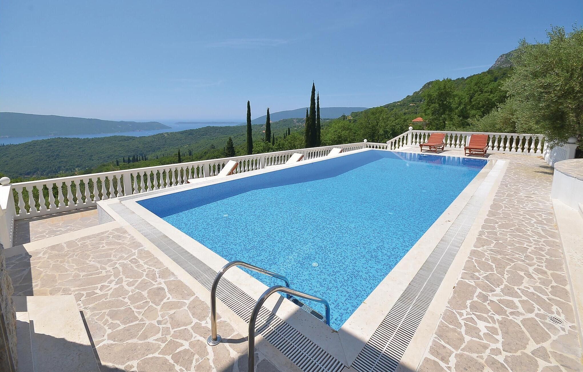 Una piscina rettangolare con bordo in pietra e scaletta in metallo.