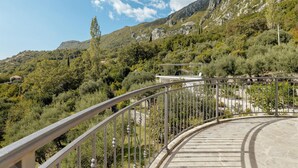 Un sentier sinueux bordé d’une rambarde métallique, entouré d’une végétation luxuriante et de montagnes rocheuses.