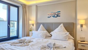 A hotel room with a large bed, two bedside tables, a wall-mounted TV, and a window with curtains. - Beautiful apartment in Binz with WiFi (Prora/Rügen)