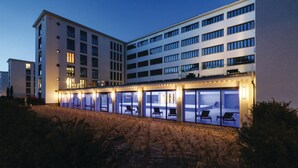 A modern hotel with multiple floors, outdoor seating area, and a pool. - Beautiful apartment in Binz with WiFi (Prora/Rügen)