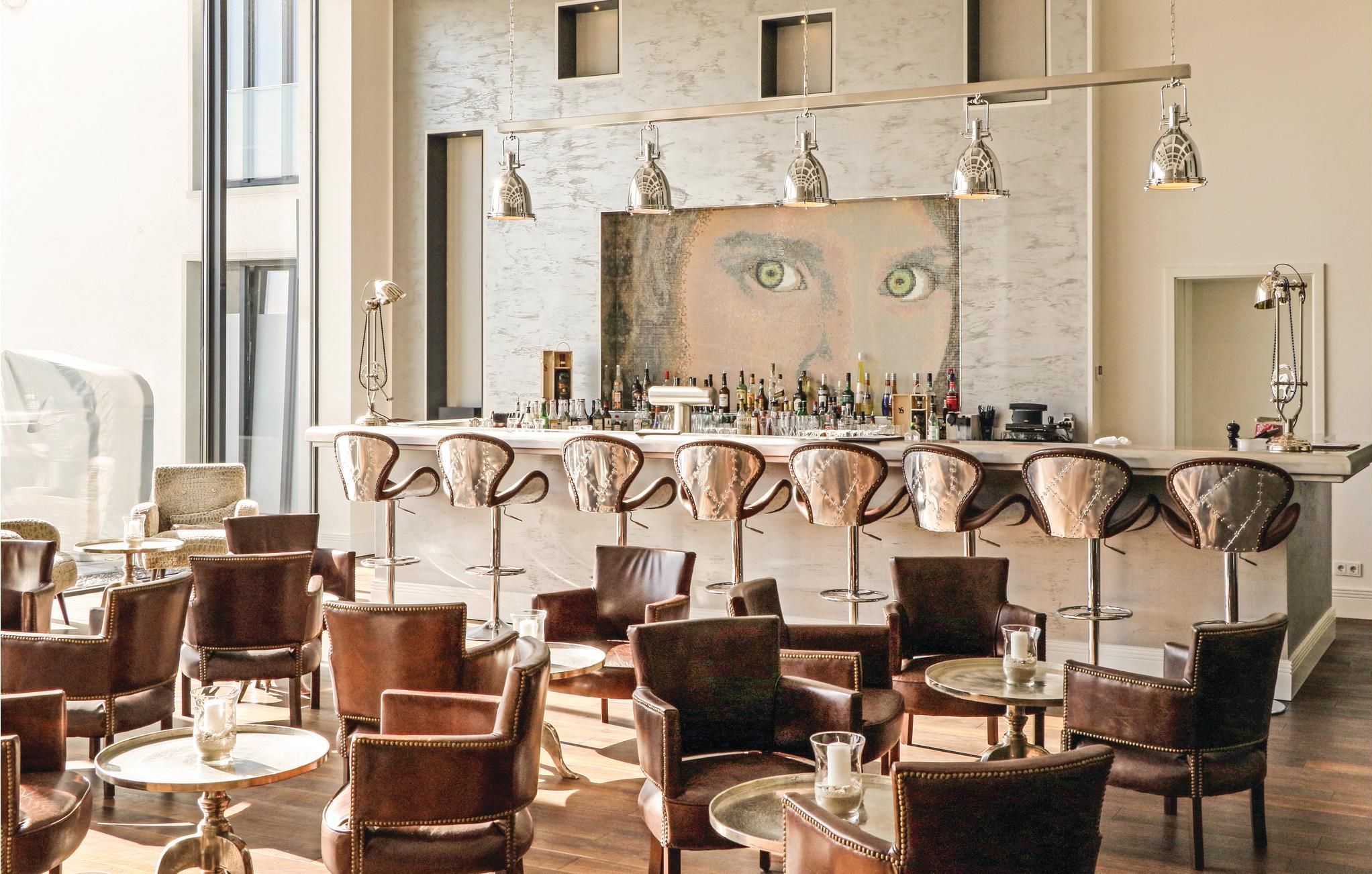A bar area with a marble countertop, multiple bar stools, and a large mirror.