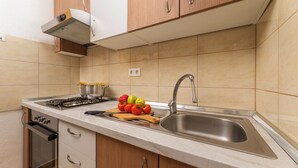 Una cucina moderna con lavello in acciaio inossidabile, mobili in legno e piano cottura a gas.