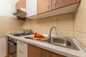 Una cocina moderna con un lavamanos de acero inoxidable, armarios de madera y una estufa a gas.