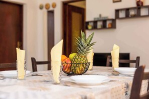 Una mesa de comedor dispuesta con platos, fruteros y servilletas.