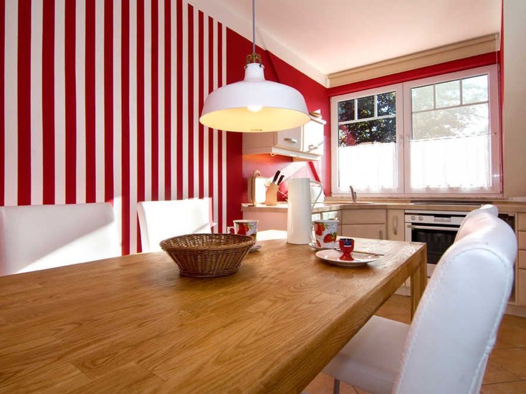 A dining area with a wooden table, white chairs, a basket, and a white pendant light.