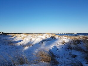 A snowy landscape with a clear sky and a distant view of a bridge over water. - Nordstrand - Holiday home Ostseesonne (Prerow)