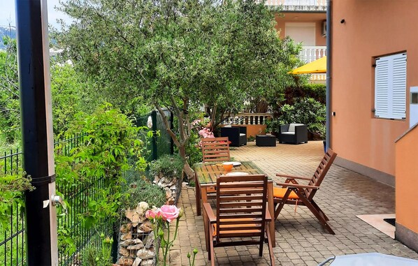 Un espace patio aménagé avec une table et des chaises, entouré de verdure et délimité par une clôture.