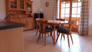 Un coin repas avec une table et des chaises en bois, un buffet en bois et un téléviseur.