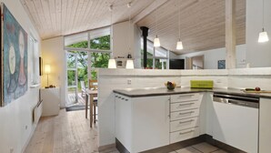 Una cocina moderna con armarios blancos, una isla central y un amplio ventanal que proporciona luz natural.