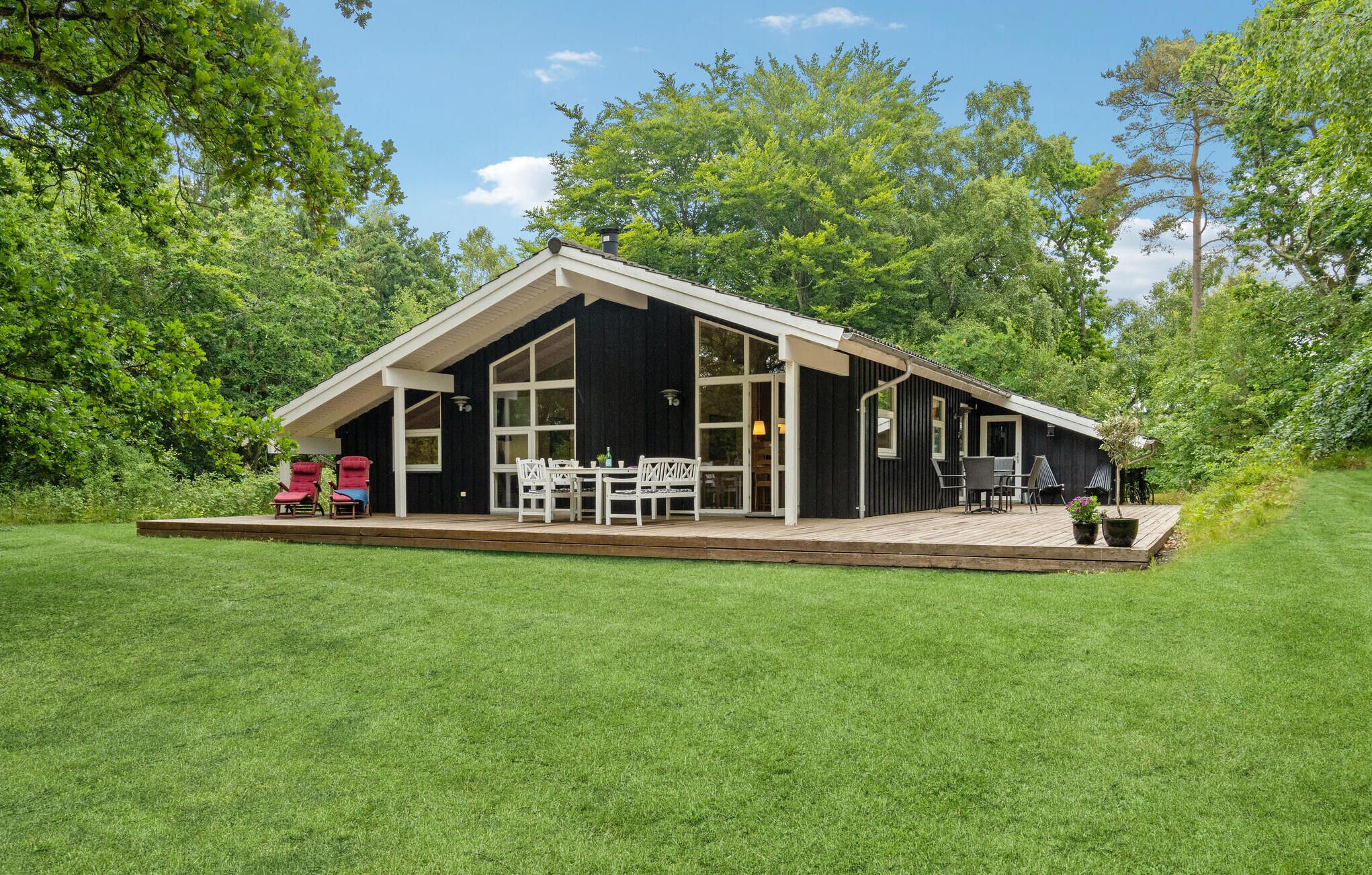 A cabin with a deck, large windows, and a patio area with outdoor seating.