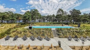 Zona de piscina con sillones de descanso y vistas al bosque circundante.