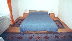 Una camera da letto con un letto, due comodini con lampade e un tappeto decorato.