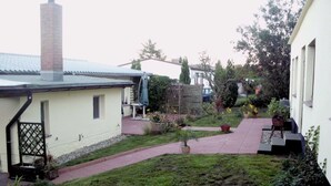 Un cortile residenziale con patio lastricato, un camino in mattoni e diverse piante in vaso.
