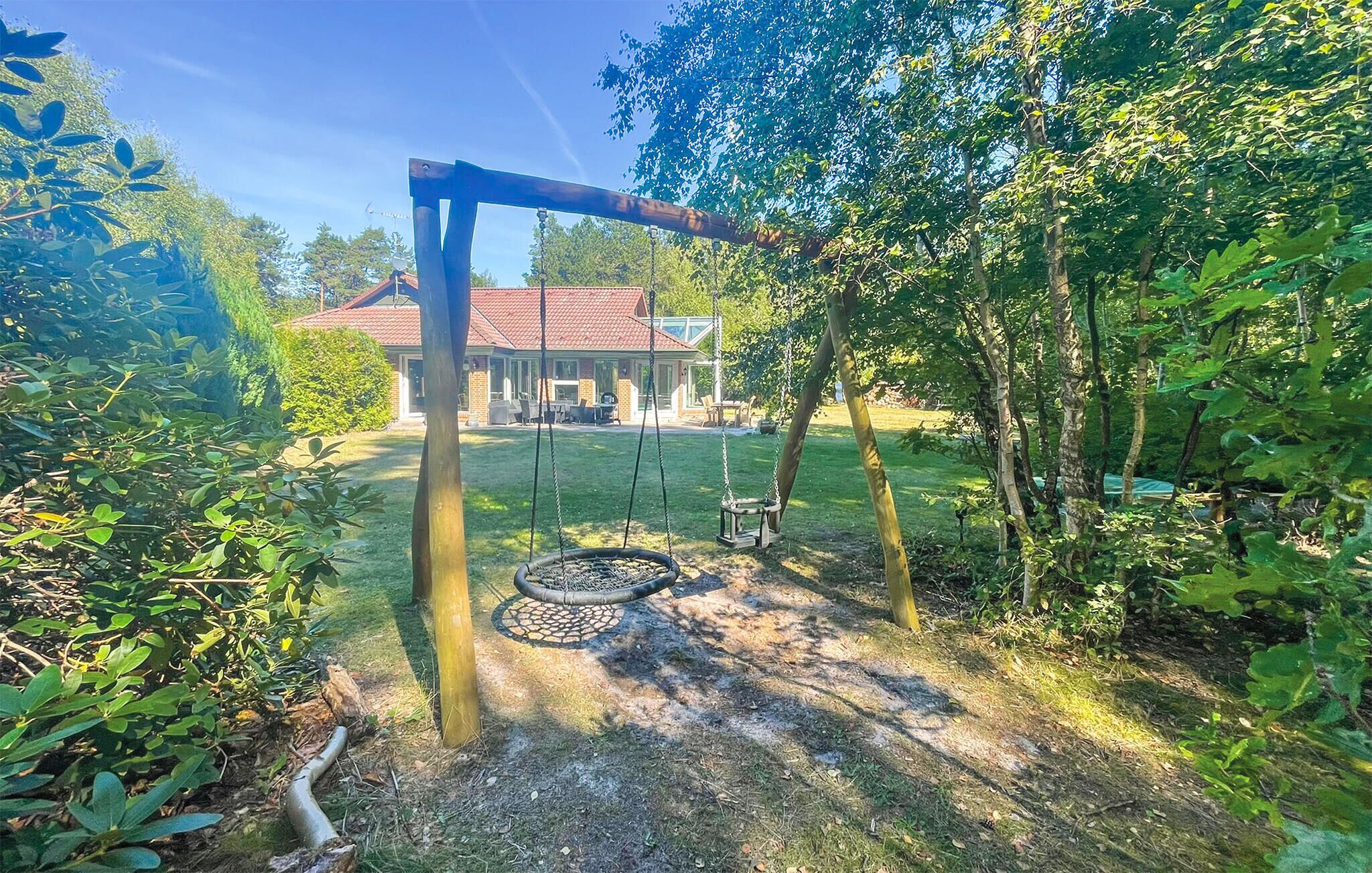 A backyard with a swing set, a tire swing, and a house in the background.