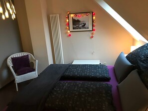 A bedroom with a bed, a chair, a radiator, and a picture on the wall. - Himmel-Blick - Vacation Apartment Himmel-Blick (Pünderich)