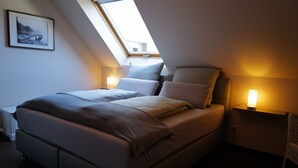 A bedroom with a bed, bedside lamps, a framed picture on the wall, and a skylight. - Himmel-Blick - Vacation Apartment Himmel-Blick (Pünderich)