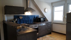 A modern kitchen with dark cabinetry, a built-in stove, and a microwave. - Himmel-Blick - Vacation Apartment Himmel-Blick (Pünderich)