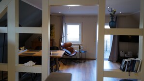 A modern living room with a dining area, a large window, and a bookshelf. - Himmel-Blick - Vacation Apartment Himmel-Blick (Pünderich)