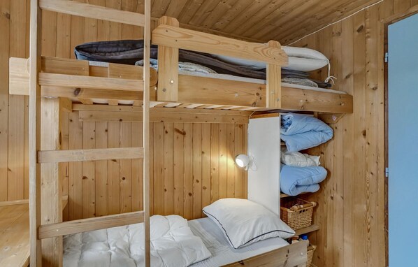A bunk bed with wooden walls and a ceiling light.