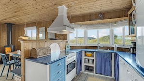 A modern kitchen with wooden walls, a large island, and a view of the outdoors. - Cozy home in Frøstrup with kitchen (Frøstrup)
