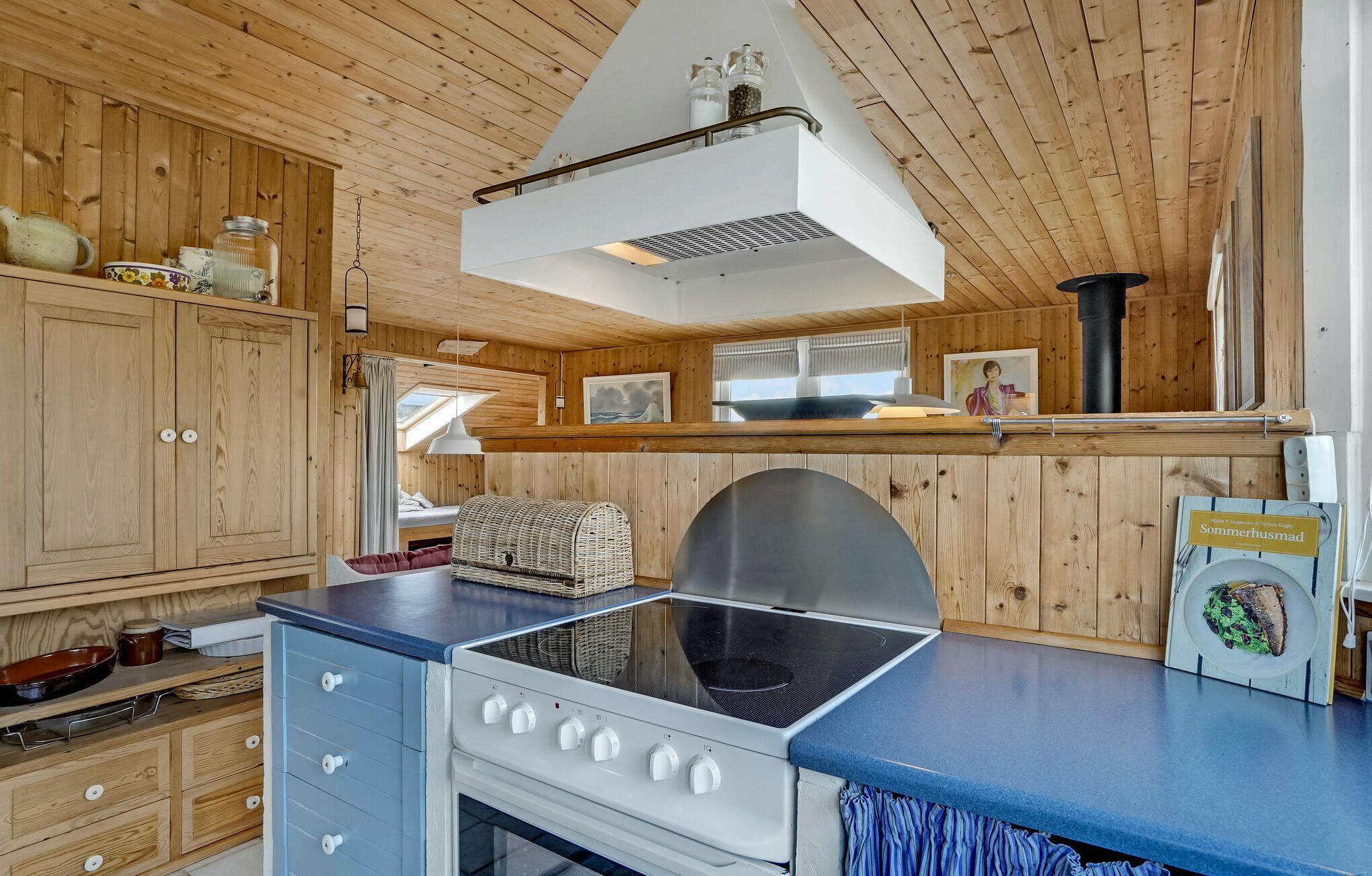 Een kleine keuken met houten kastjes, een fornuis en een eethoek met een tafel en stoelen.