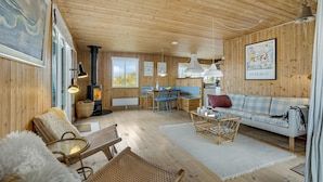 A cozy cabin interior with a wooden interior, a fireplace, a dining area, and a sofa. - Cozy home in Frøstrup with kitchen (Frøstrup)