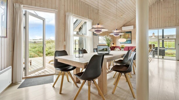 A spacious dining area with a wooden table and chairs, large windows, and a view of the outdoors. - Cozy home in Hvide Sande with sauna (Hvide Sande)