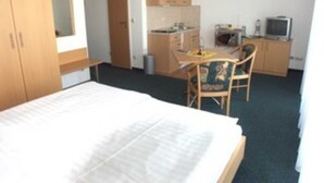 Ein Hotelzimmer mit Bett, Schreibtisch, Stuhl und Fernseher.