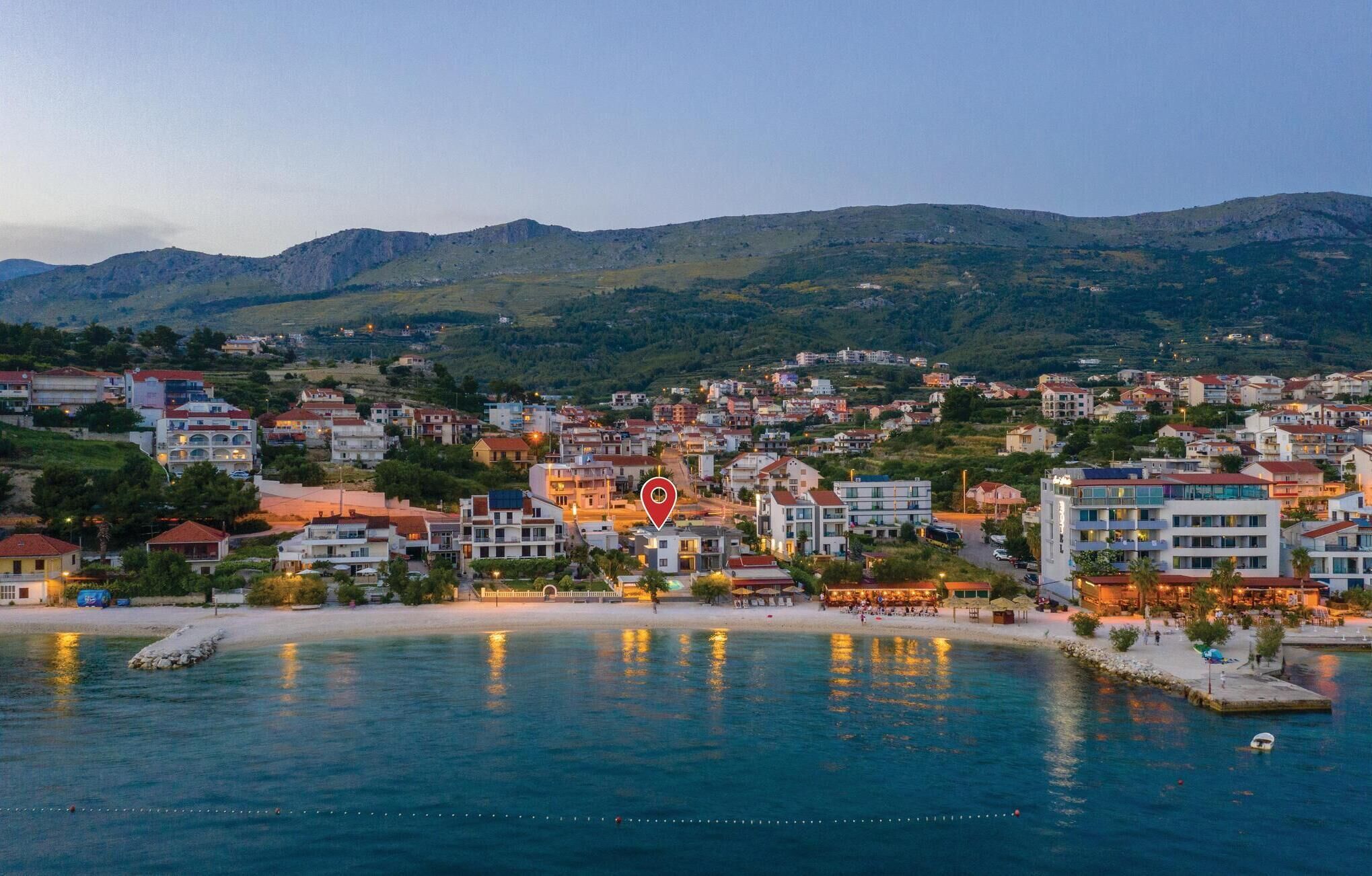 A coastal town with buildings along the waterfront, a pier, and a mountainous backdrop.