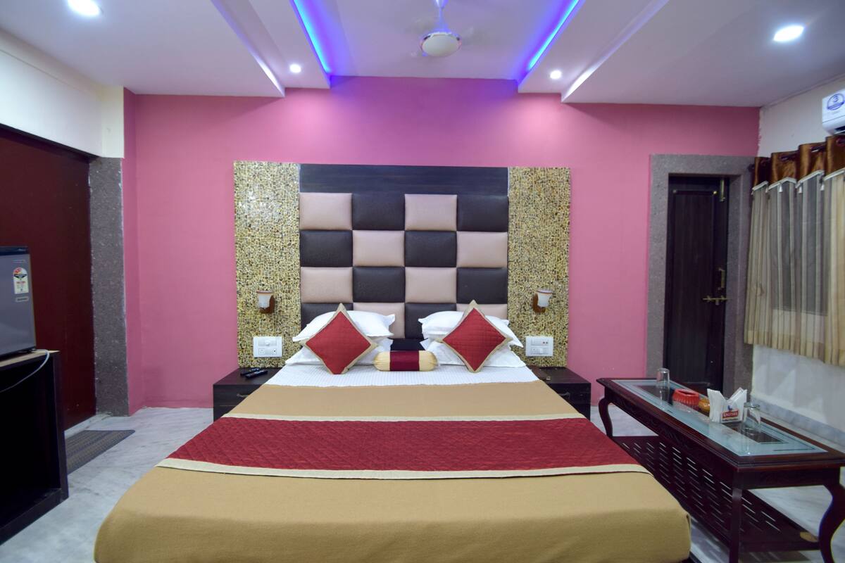 Una habitación de hotel con una cama grande, un cabecero de estampado a cuadros y una pared de acento roja.