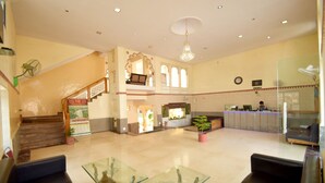A spacious lobby with a staircase, seating area, reception desk, and a chandelier. - Menal Jungle Safari Resort (Begun)