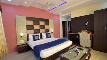 A modern hotel room with a large bed, a glass coffee table, a wardrobe, and a ceiling fan.