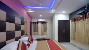 A modern hotel room with a large bed, a wardrobe, and a ceiling with blue LED lighting. - Menal Jungle Safari Resort (Begun)