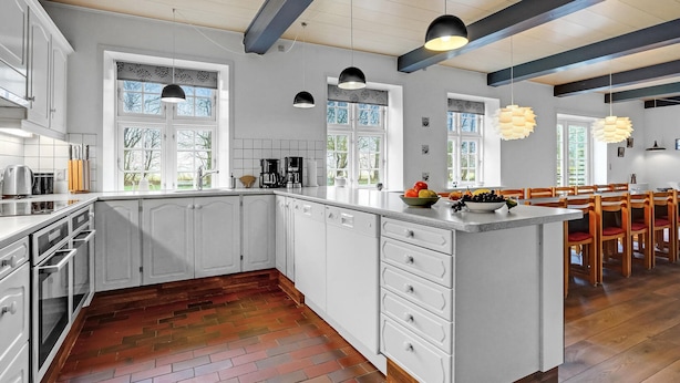 A modern kitchen with white cabinetry, a large island, and pendant lighting.