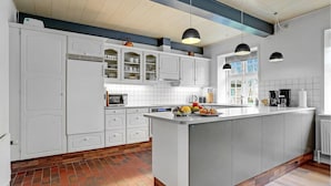 A modern kitchen with white cabinetry, a central island, and a large window providing natural light.