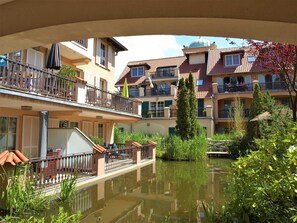 Un hotel a più piani con balconi, un cortile interno e un piccolo stagno.