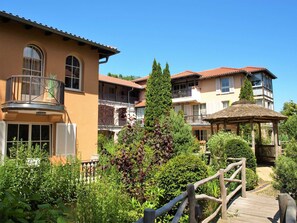 Un hotel con diversi balconi, un pontile in legno e vegetazione rigogliosa.