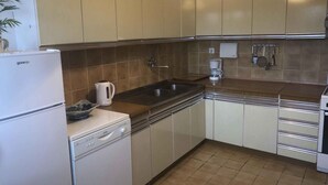 A compact kitchen with white appliances, a sink, and a coffee maker.
