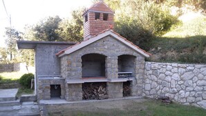 A stone-built outdoor kitchen with a chimney, a sink, and a fire pit area.