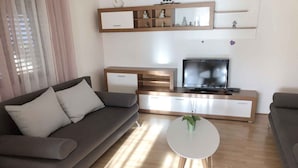 A modern living room with a grey sofa, a white coffee table, and a TV on a wooden cabinet.