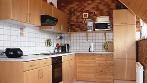Une cuisine avec des meubles de rangement en bois, un four à micro-ondes, un grille-pain et une machine à café.