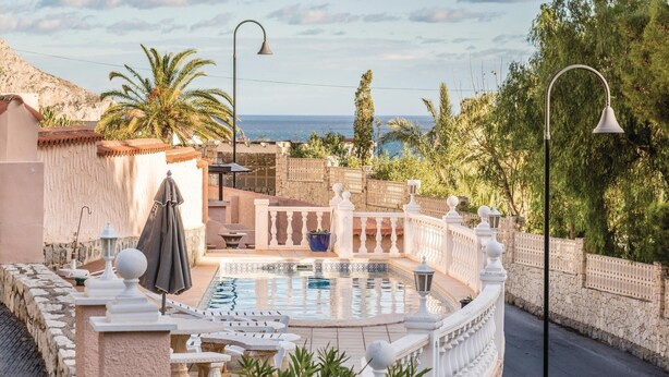 A pool area with a stone wall, lounge chairs, and a view of the sea. - Awesome home in Altea (Altea)