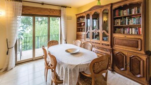 A dining area with a round table, chairs, a wooden bookcase, and a balcony with curtains. - Awesome home in Altea (Altea)