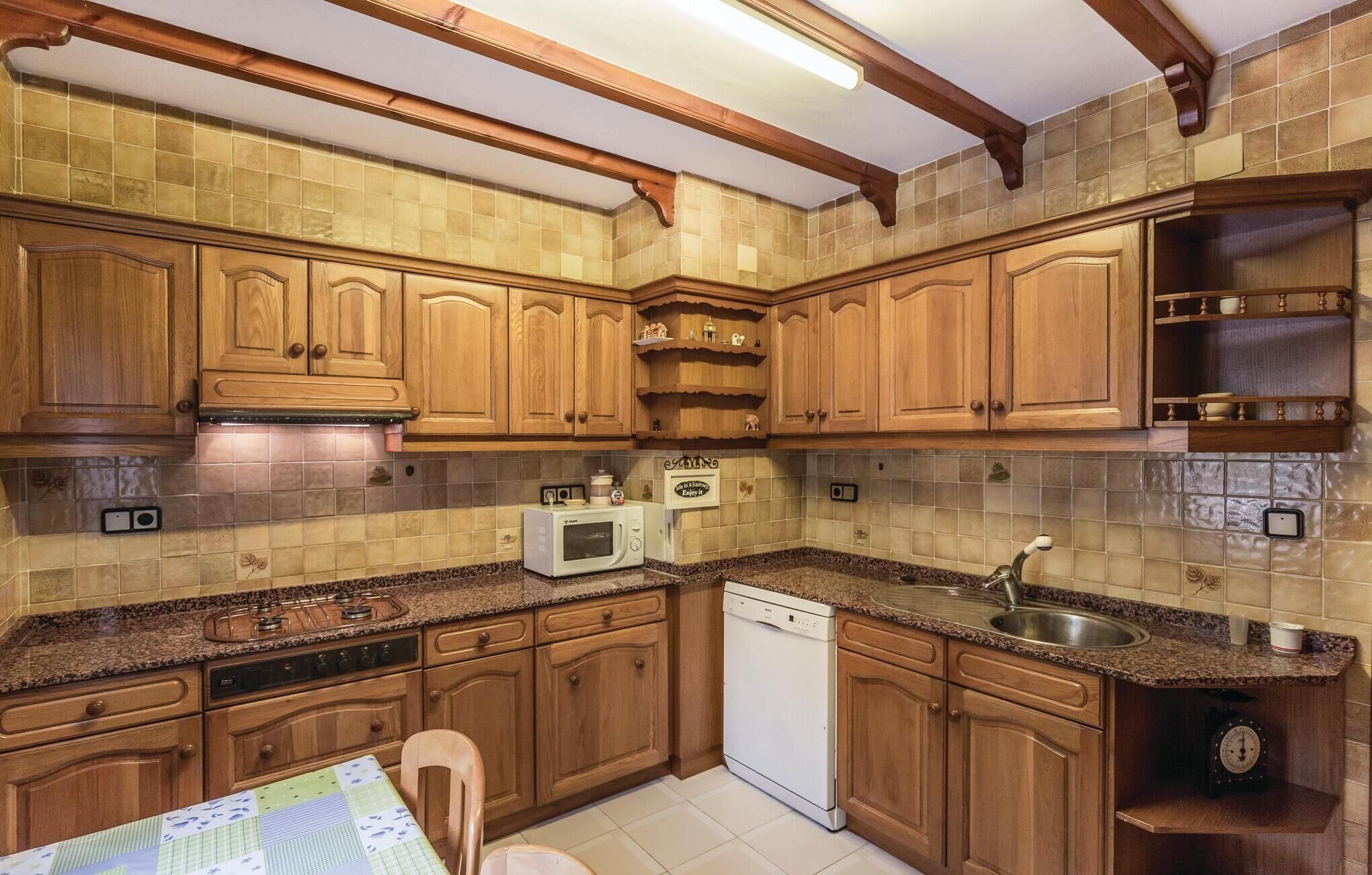 A kitchen with wooden cabinets, a microwave, a dishwasher, and a sink.