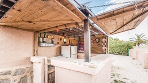 A rustic outdoor bar area with a wooden structure, a stone wall, and various signs including 'SECRET BAR' and 'Café Bistro Water Front'. - Awesome home in Altea (Altea)