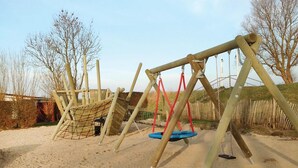 Un parque infantil con columpios y una estructura para escalar.