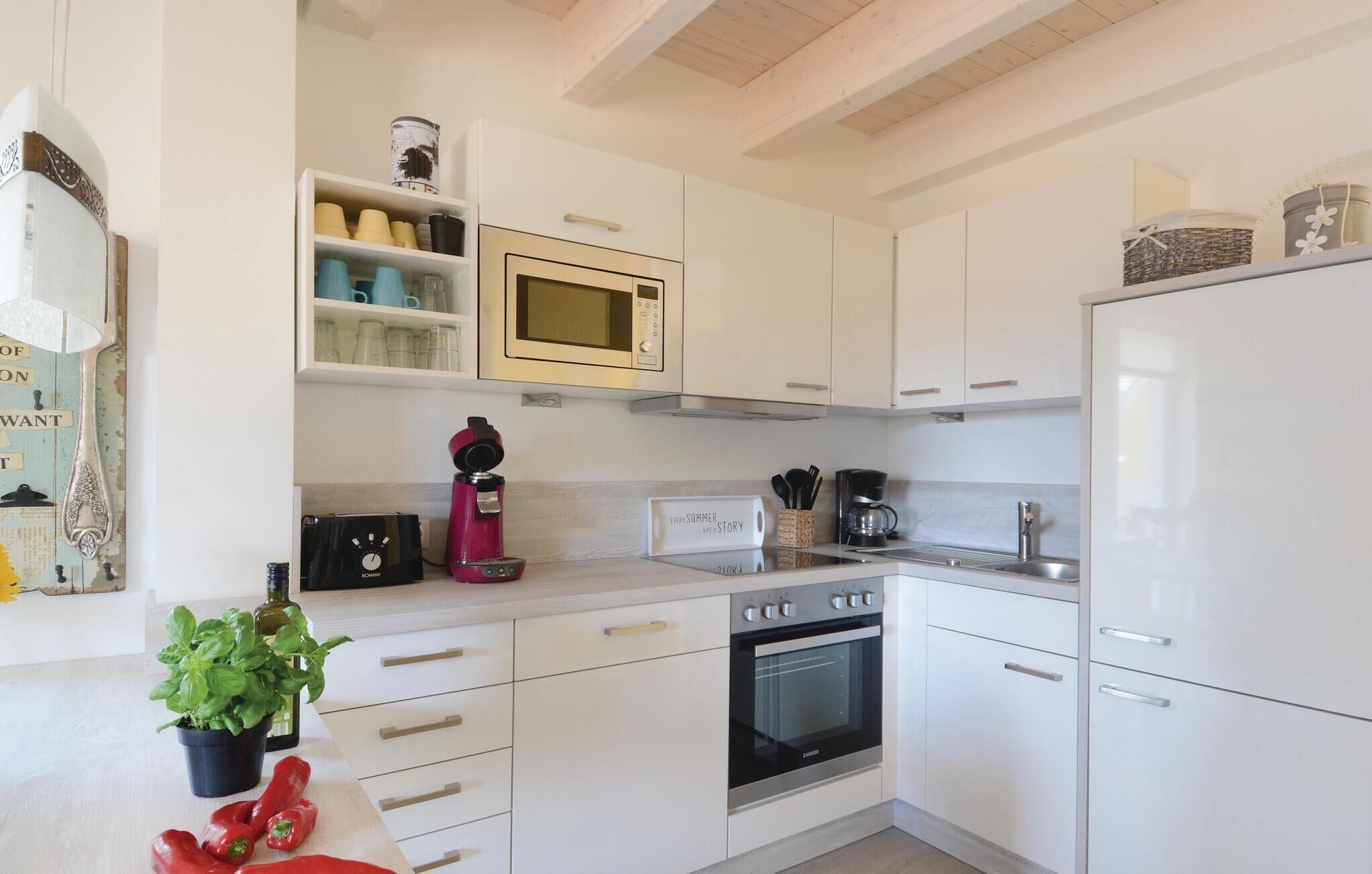 Una cocina moderna con armarios blancos, microondas, cafetera y estufa.